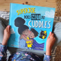 Close up of child sat holding the Superjoe does not do cuddles childrens book on a wooden floor