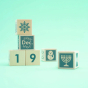 Uncle Goose kids plastic-free wooden perpetual calendar toy blocks scattered on a blue background