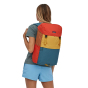 Woman stood on a white background wearing the Patagonia eco-friendly arbor lid backpack in the surfboard yellow colour