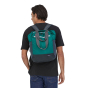 Man stood wearing the Patagonia ultralight black hole tote pack in the borealis green colour