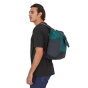 Man stood wearing the Patagonia ultralight black hole tote pack in the borealis green colour on a white background