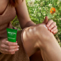 A close up of a person applying the Weleda Skin Food to their knee. They are holding the tube in one hand 
