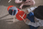 Overhead view of the Plan Toys Musical Band Children's Drum Kit being played by a toddler, an eco-friendly and plastic-free wooden drum kit for toddler's.
