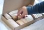 Close up of childs hand picking an Abel Golden Ratio toy block out from the box