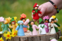 Close up of a hand picking up an Ambrosius plastic free strawberry doll from a group of Ambrosius spring fairy figures


