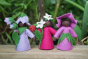 Close up of the Ambrosius handmade Harebell, Raspberry and Purple Morning Glory collectable dolls on a wooden background in front of some green plants