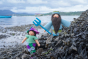 Close up of an Ambrosius King Neptune and Purple Mermaid collectable felt dolls in some seaweed in front of the ocean 