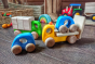 Close up of some Bajo plastic-free wooden vehicle toys on a grey wooden floor