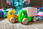 Close up of Bajo plastic-free wooden truck with blocks toy on a carpet in front of a child's legs