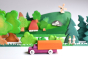 Bumbu wooden waldorf lorry toy on a white table in front of a green wooden toy landscape scene 