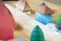 Close up of the Bumbu eco-friendly Oltenia miniature toy house on a wooden table next to a grapat mandala tree