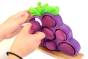 Close up of hands playing with the Bumbu  slotting grapes toy set on a white background