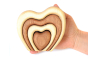 Hand holding the wooden Bumbu stacking heart in front of a white background