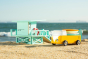 Candylab solid wooden campervan toy on a sandy beach next to a wooden beach hut toy