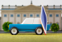 Candylab blue wooden suv toy with a miniature wooden kayak on a green background in front of a model palace