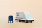 Candylab collectable wooden mail van toy on a beige background next to a miniature blue postbox