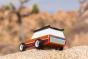 Close up of the Candylab solid wooden big sur car toy on a large rock in front of a beige background