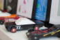 Candylab black, white and red race car toy on a white shelf next to other Candylab cars and some children's drawings
