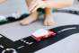 Close up of the Candylab red racing car toy on a rubber road set in front of a childs feet