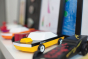 Candylab plastic-free yellow and black car toy on a shelf next to other Candylab toy cars and some children's drawings