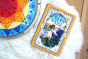 A picture of the Cinder & Ella book by Barbara Slade placed on a white fluffy rug next to the Grimm's sparkling mandala
