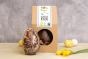 Cocoa Loco eco-friendly marbled chocolate easter egg on a cream worktop next to its cardboard packaging and some daffodils