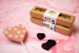 Cocoa Loco champagne truffles box next to a pink heart lollipop and some dark chocolate hearts on a pink background