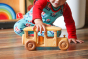 young child crawling on a wooden floor playing with a debresk eco-friendly wooden bus toy