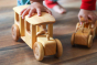 close up of childs hands holding the eco-friendly wooden Bus and Oldtimer from debresk on a wooden floor