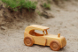 Close up of a Debresk eco-friendly wooden oldtimer car on some each sand in front of a small patch of grass