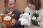 2 children smiling and looking at the Fabelab soft Christmas reindeer, yeti and Christmas tree cuddly toys