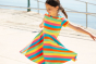 Child spinning around wearing the Frugi Rainbow Stripe Spring Skater Dress