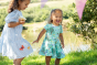 Children playing outdoors, one is wearing the  Frugi Beach Hut Blue and white Stripe Cassie Collared Dress