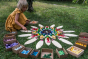 Young girl laying out Grapat mandala toy pieces on the plastic-free petal blocks on some green grass
