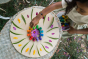 Close up of a girl lining up Grapat eco-friendly wooden rainbow mandala mushrooms in a circle on a wooden board