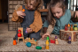 Two young children playing with a range of multicoloured wooden Grapat toys on the floor.