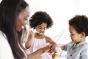 Woman and two children using Jack N Jill toothbrushes and toothpaste in a white room