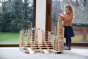 Girl stacking up Just Blocks plastic-free wooden shapes in a large tower on a grey carpet 