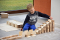Young boy playing with a wooden ball run made using Just Blocks Smart Lines on a grey carpet