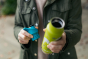 Close up of hands holding a Klean Kanteen insulated bottle and a replacement sports lid