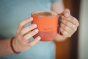 Close up of some hands holding a Klean Kanteen 14oz insulated spill-proof mug, filled with coffee