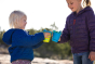 Two children stood, holding up some Klean Kanteen kids metal drinks cups with sippy lids