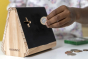 Close up of a hand putting a coin into the Koa Koa make your own money box