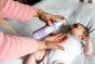 Close up of woman's hand pumping the Kokoso organic coconut baby oil lotion into her hand above a baby