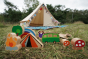 Close up of the Lanka Kade dan y ser wooden toy set on some grass in front of a beige tent