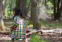 Child wearing LGR winter check reversible day after day dress in the woods