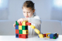 Girl stacking blocks from the Naef multicoloured Ligno toy set on a white table