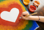 Close up of child's hand painting and rainbow heart with the Natural Earth kids eco-friendly paint set