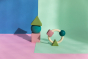 Oli & Carol X Bauhaus Movement Floating Geometric Blocks in Pastel colours and teething ring pictured on a pastel pin, blue and mint green block coloured background