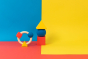 Oli & Carol X Bauhaus Movement Teething Ring and geometric shape figures pictured on a red, yellow and blue block coloured background 
